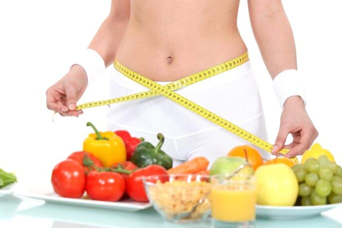 La fille mesure la taille sur fond de nourriture